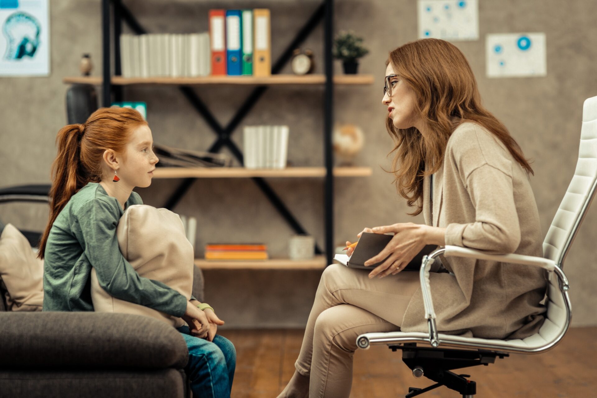 Young patient. Pleasant professional therapist holding her notes while speaking to her patient